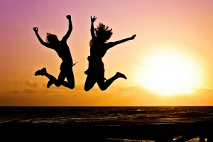 Foto: Schattenbild zweier Jugendlicher die am Strand einen Luftsprung machen