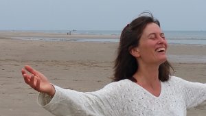 Foto: Luna am Strand, lachend mit ausgestreckten Armen